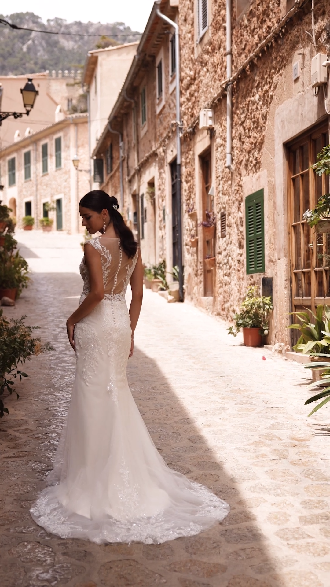Bride wearing a sparkly lace wedding dress with cap sleeves and illusion back with crystal buttons
